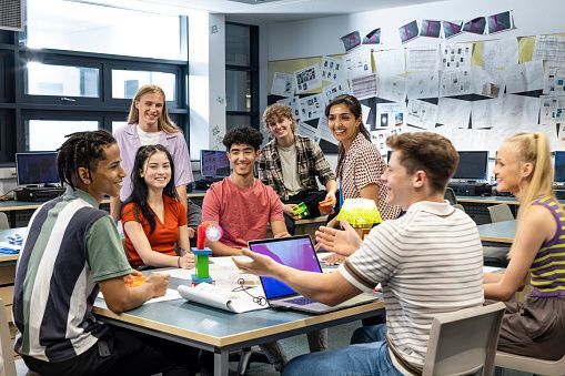 A class of students sits around a table, collaborating on a lesson.