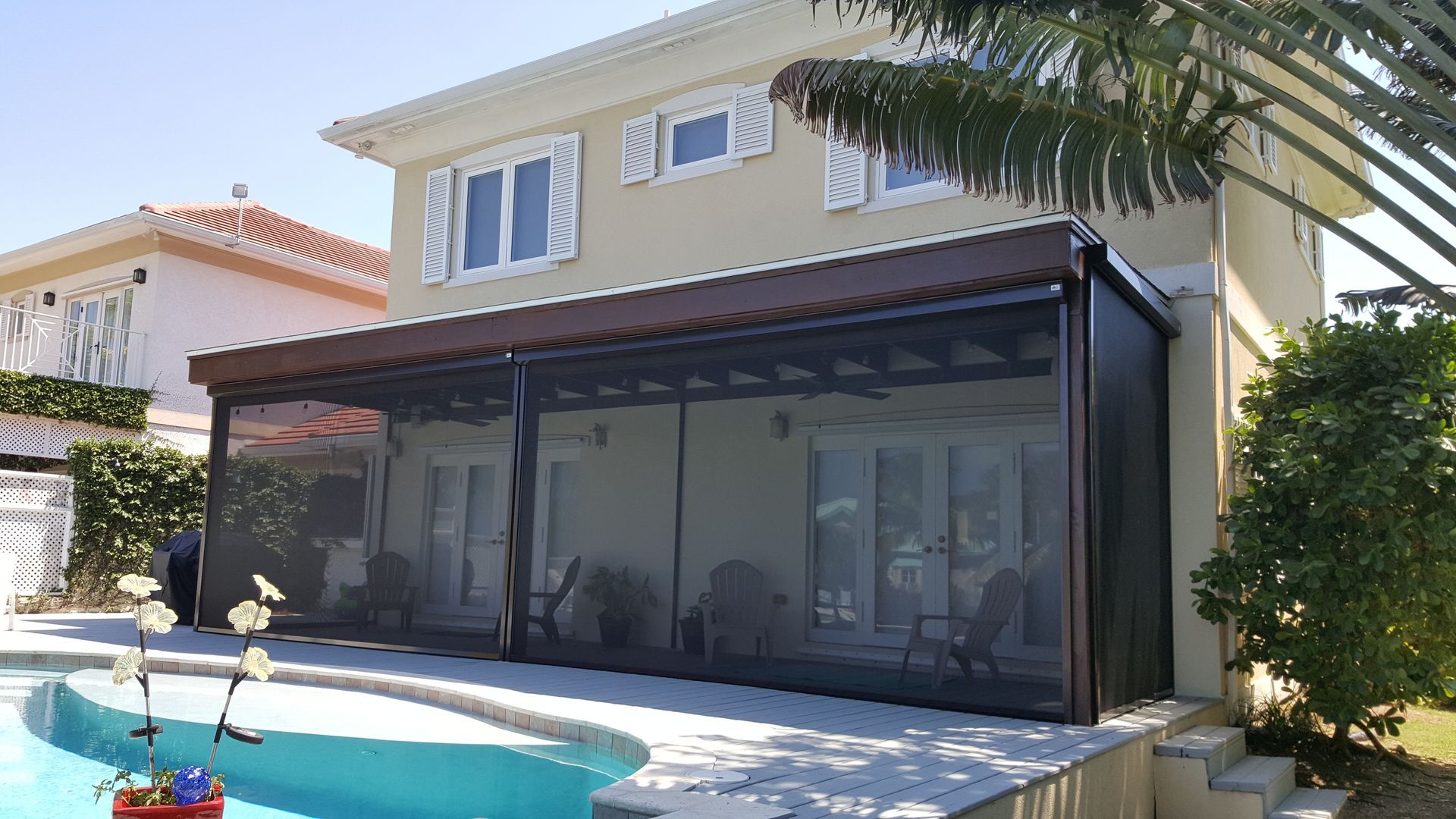 A house with a screened in porch next to a pool.