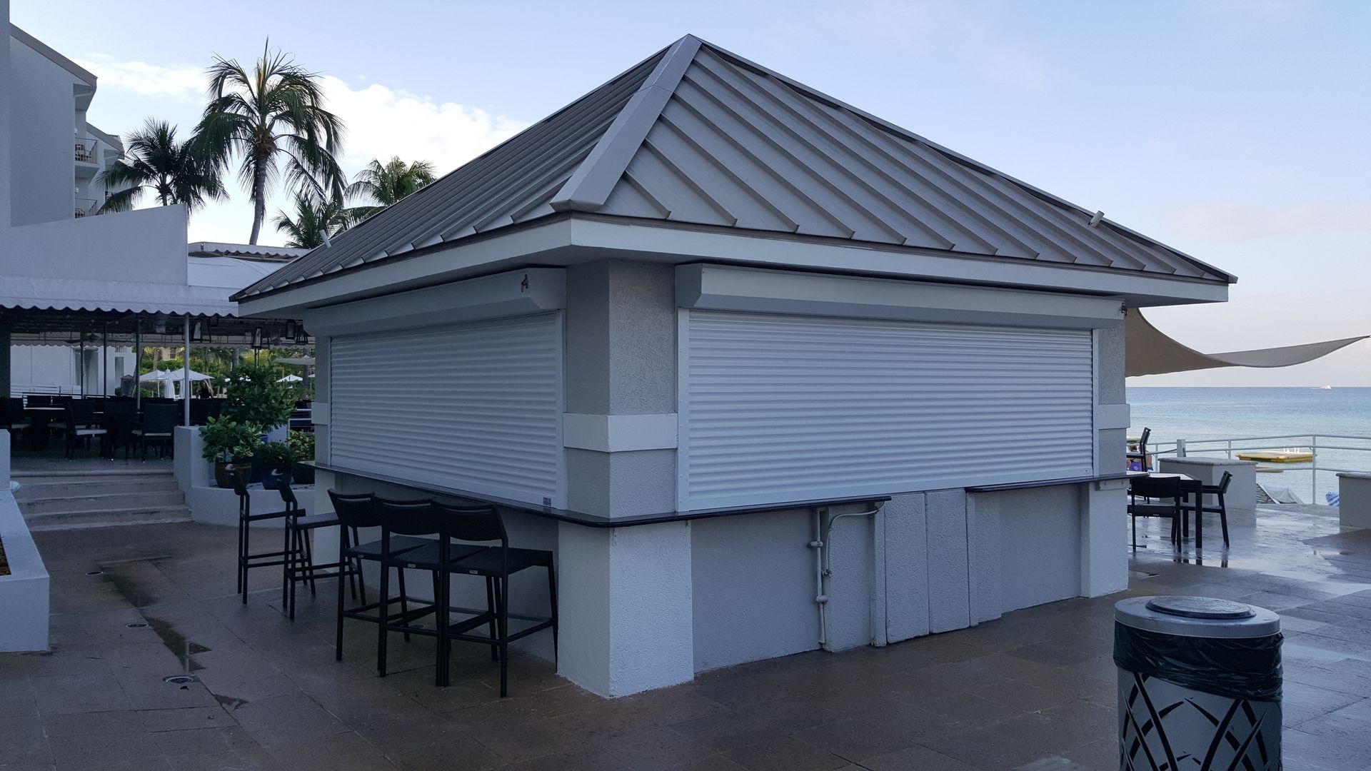 A white building with a metal roof and shutters on the windows