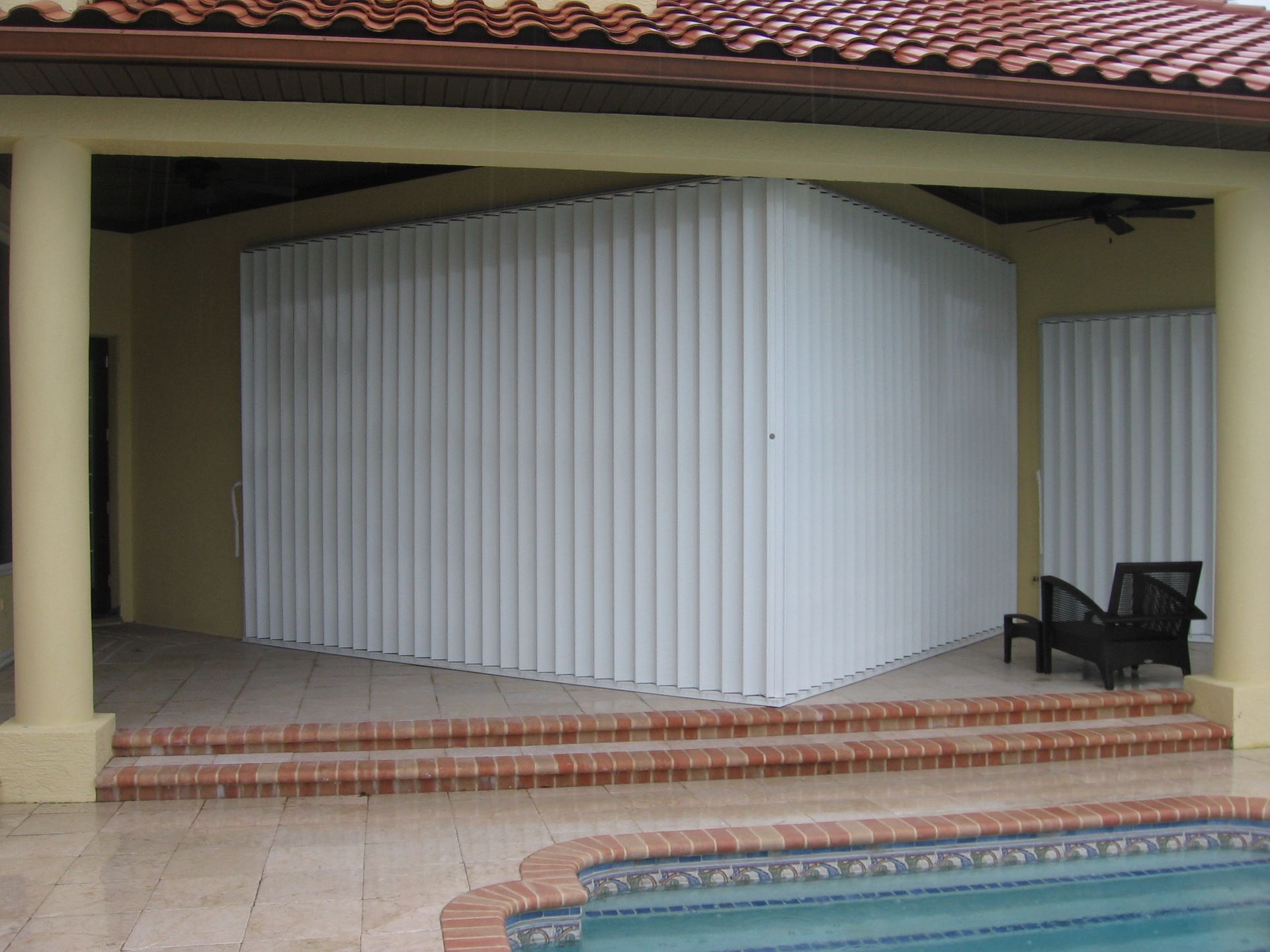 A patio with a swimming pool in the background