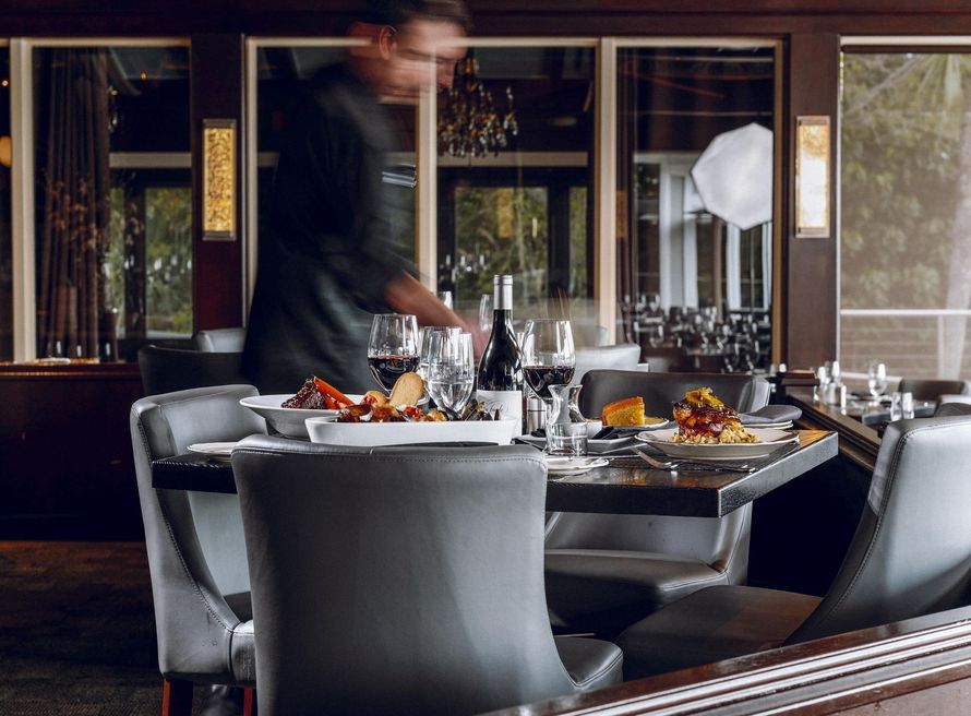 Dining table set in a modern restaurant, with a blurred server in the background.