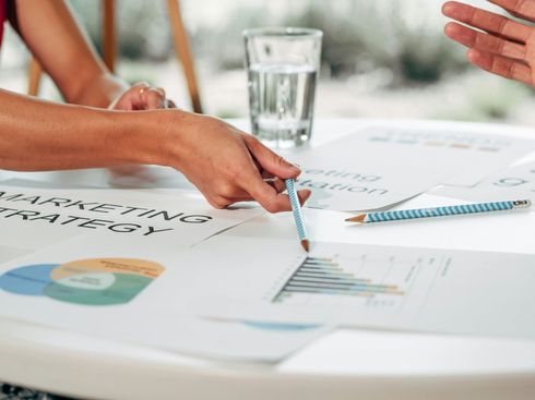 Hands pointing at charts and notes during a meeting table discussion