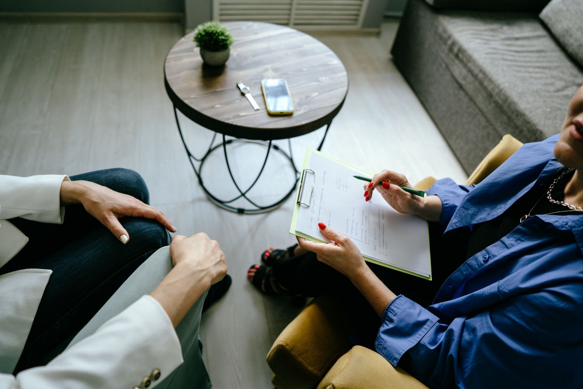 Therapist with clipboard and client in an office, discussing.