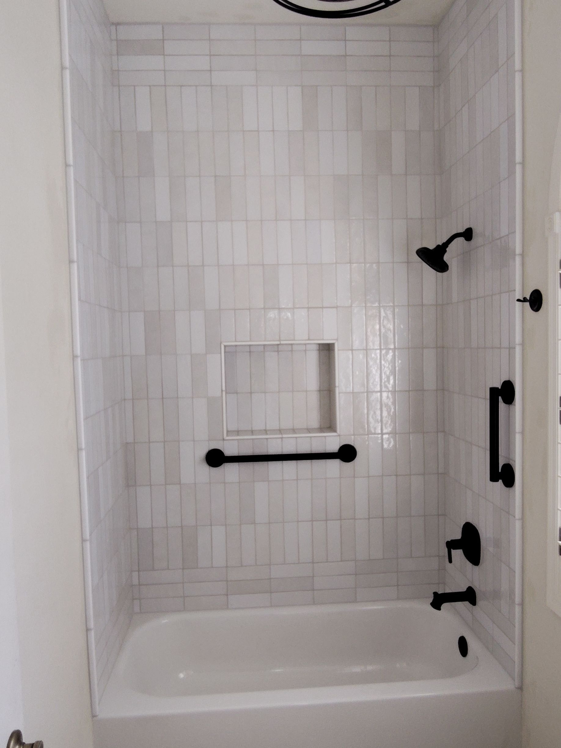 There is a bathtub in the shower with white tiles.