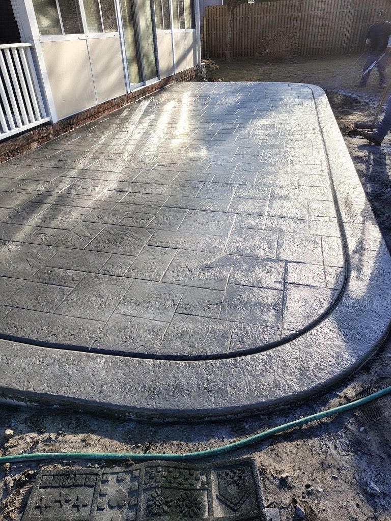 Raised concrete slab with a black cable around it in a fenced outdoor yard