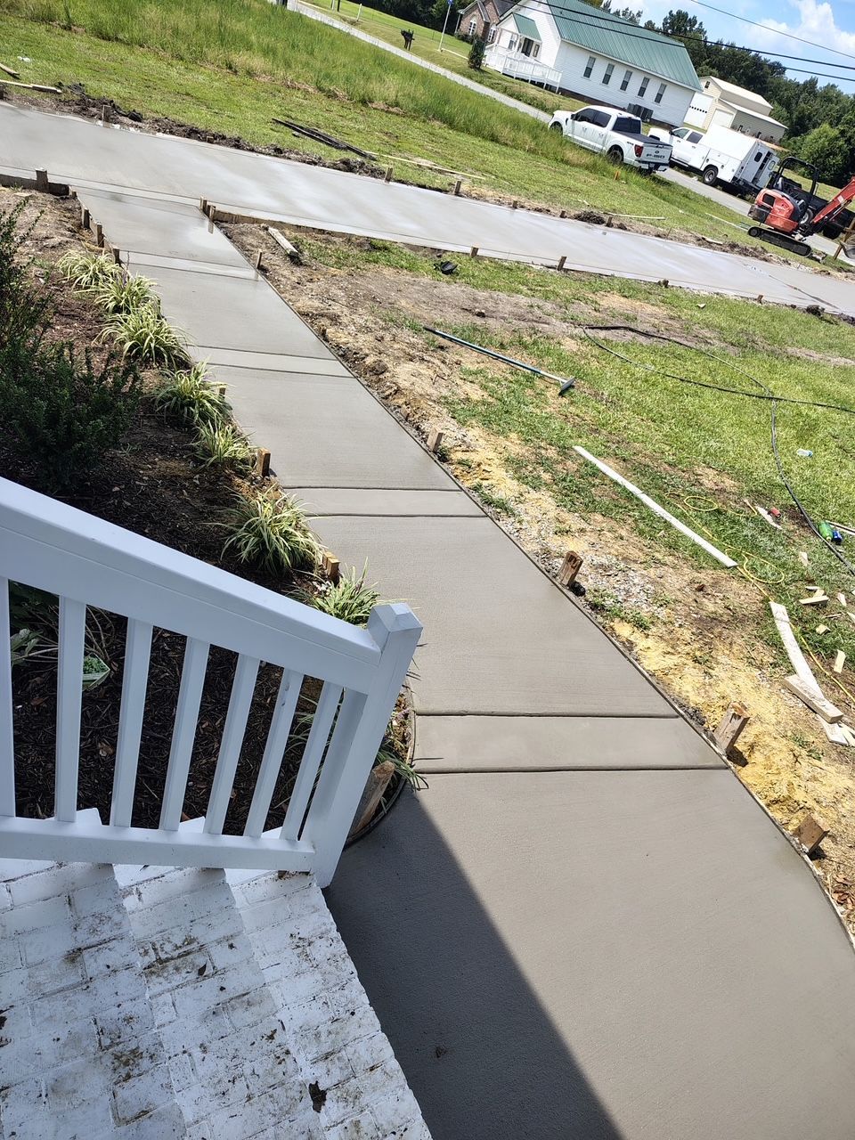 Front porch steps leading to a curved concrete walkway beside a grassy yard and street.
