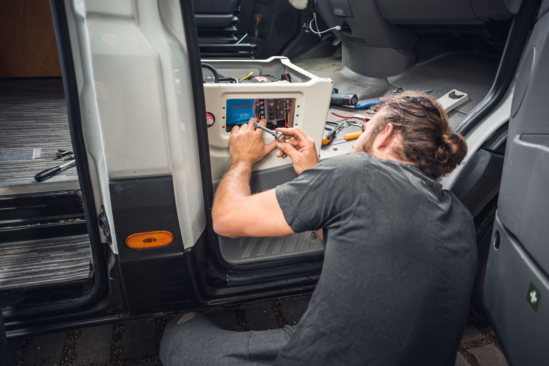 A man is kneeling down in the back of a van.