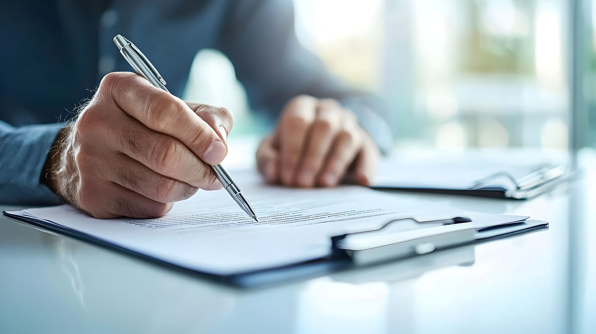 A man is writing on a clipboard with a pen.