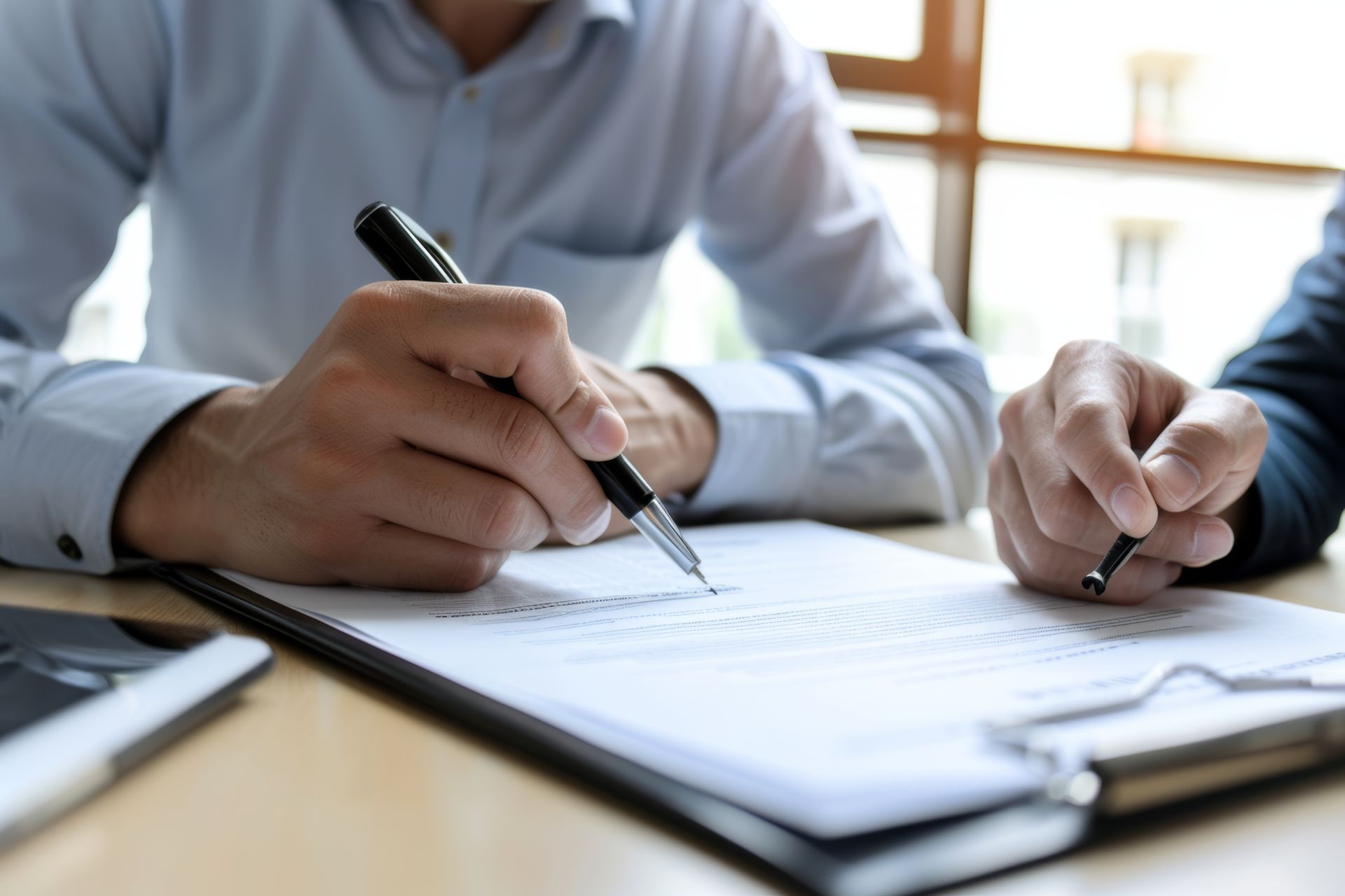 Two men are sitting at a table writing on a piece of paper.