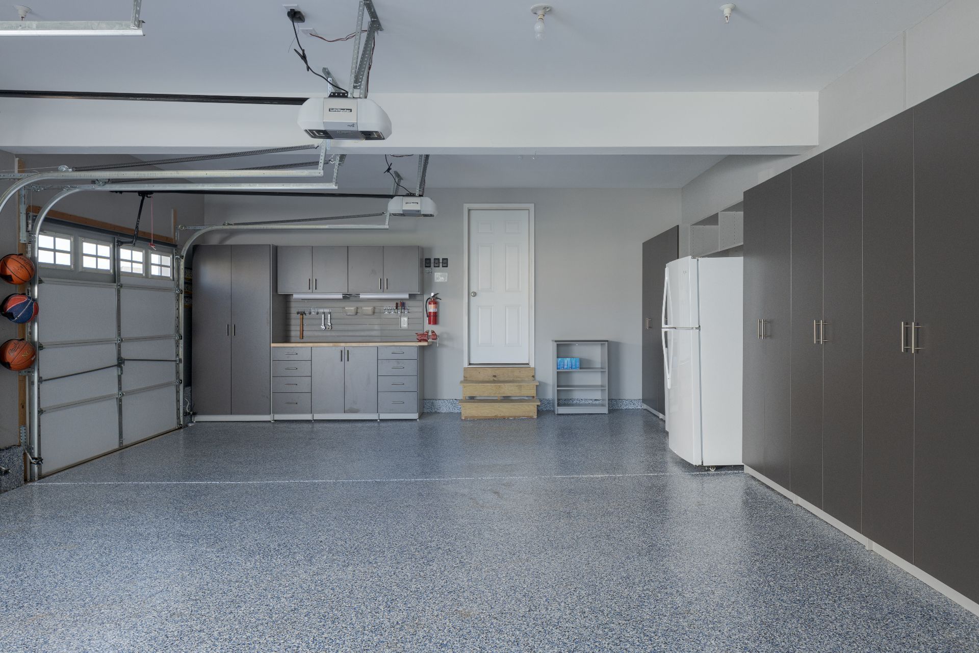 A well-organized white pantry with shelves stocked with food items, bottles, and a rotating corner storage unit.