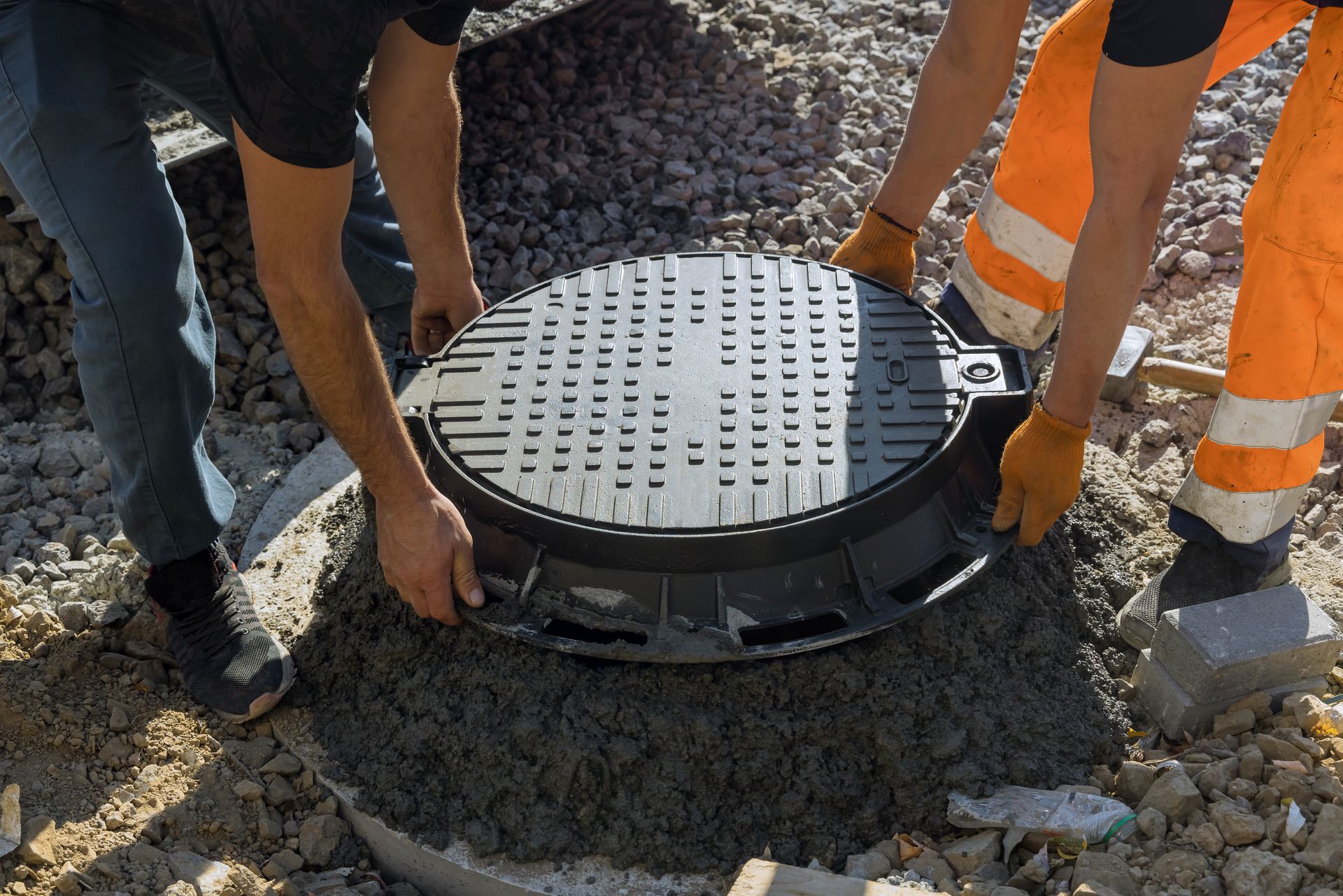 two men are working on a manhole cover in the dirt