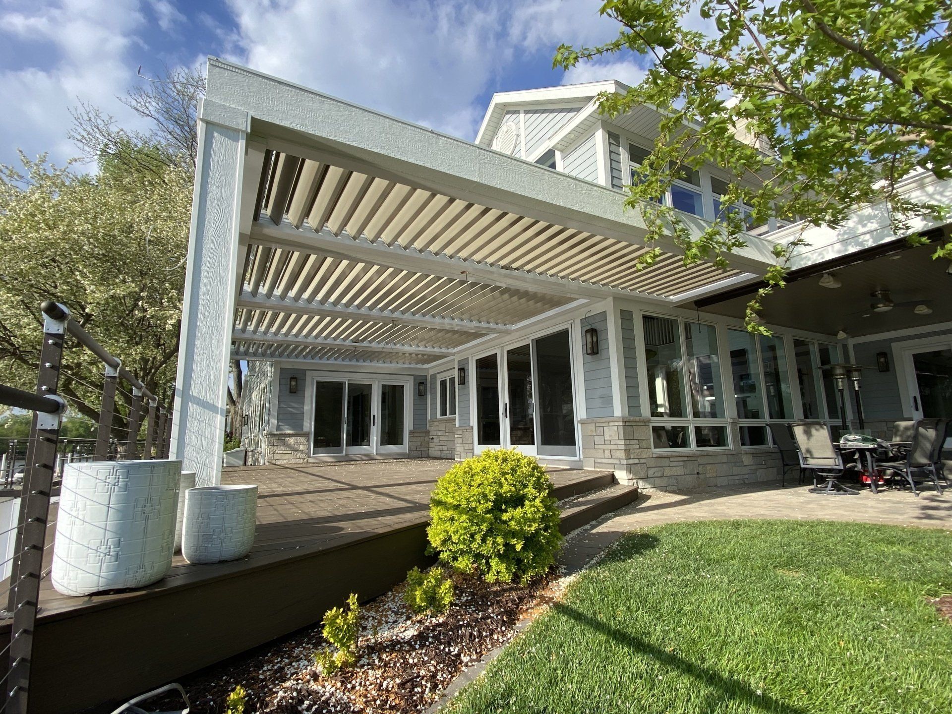 A large white house with a motorized pergola over the patio.