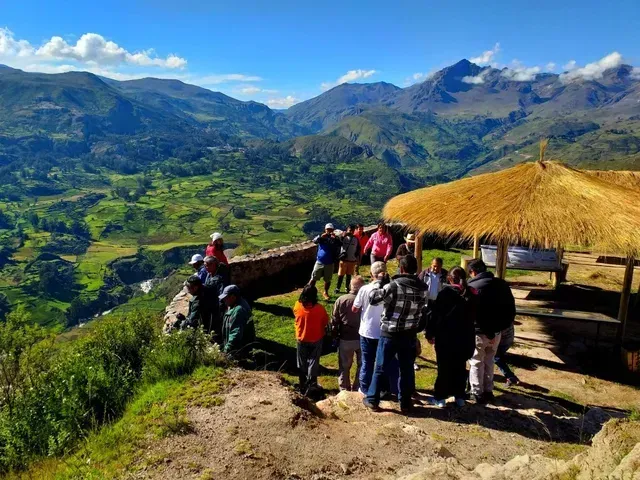 Grupo de personas en un mirador de montaña con una cabaña de techo