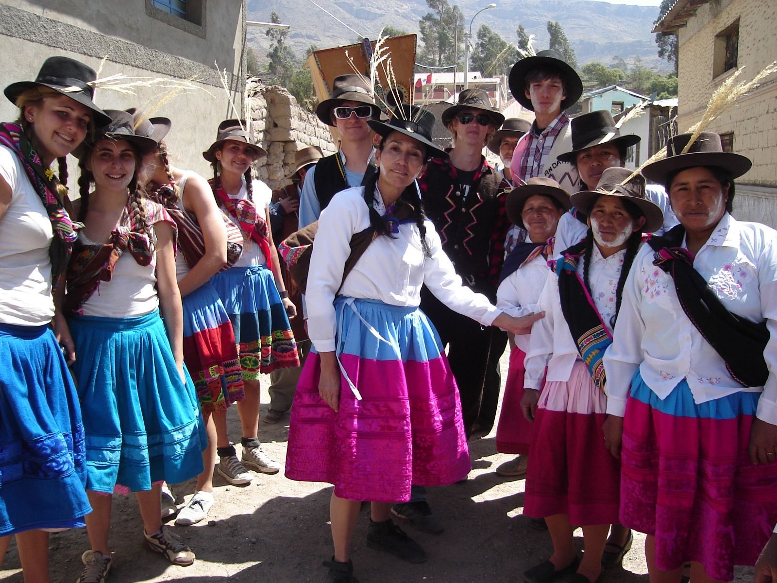 Grupo de personas con coloridos trajes tradicionales posando al aire libre en una calle soleada.