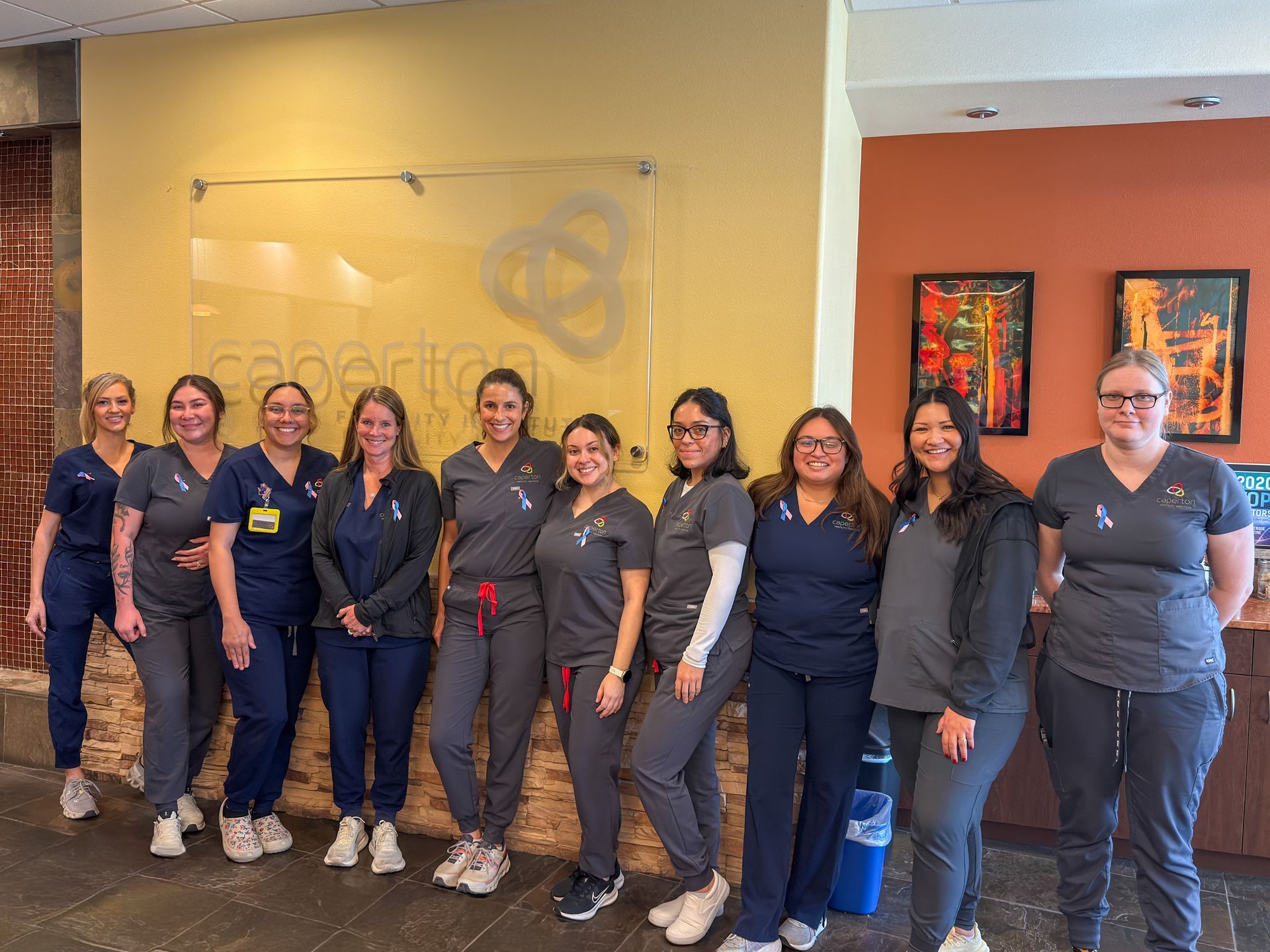 Clinic staff pose for a photo infront of the Caperton Logo.
