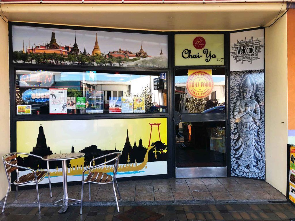 The outside of a restaurant with tables and chairs in front of it