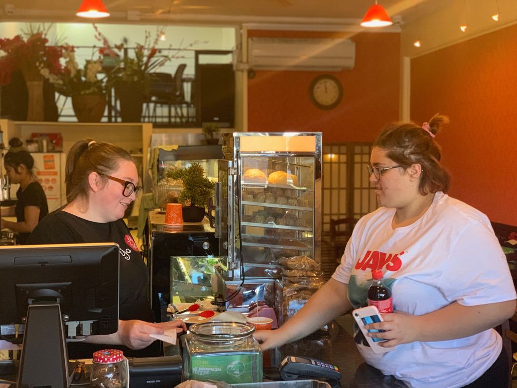 Two women are standing at a counter in a restaurant