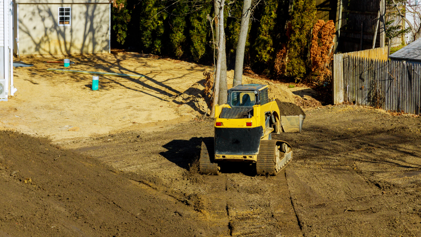 A yellow bulldozer is moving dirt in a yard.