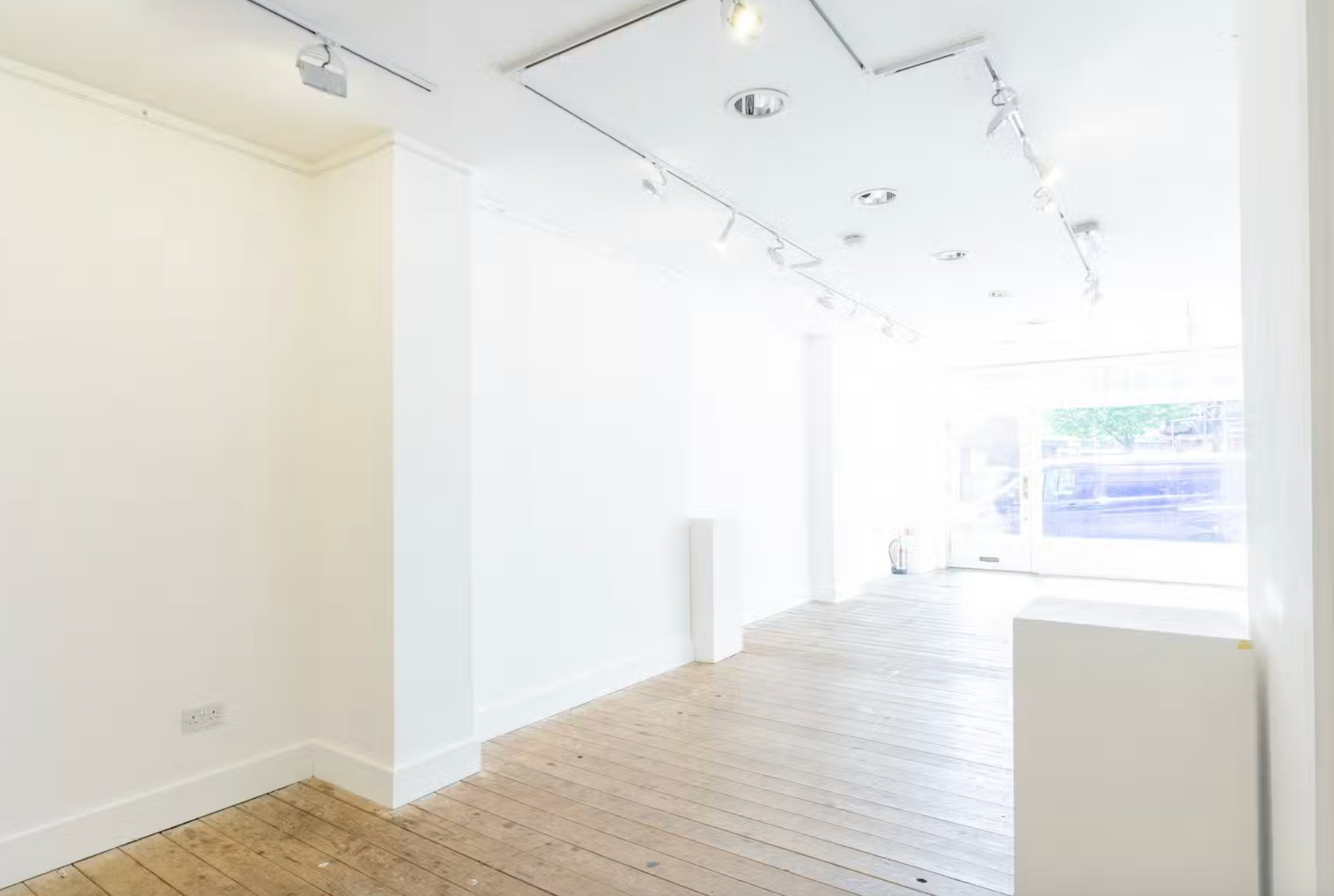 An empty room with a wooden floor and white walls