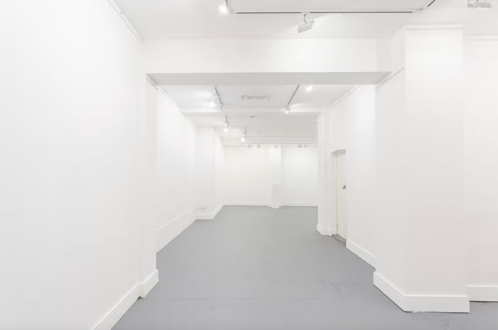 A large empty room with white walls and a gray floor.