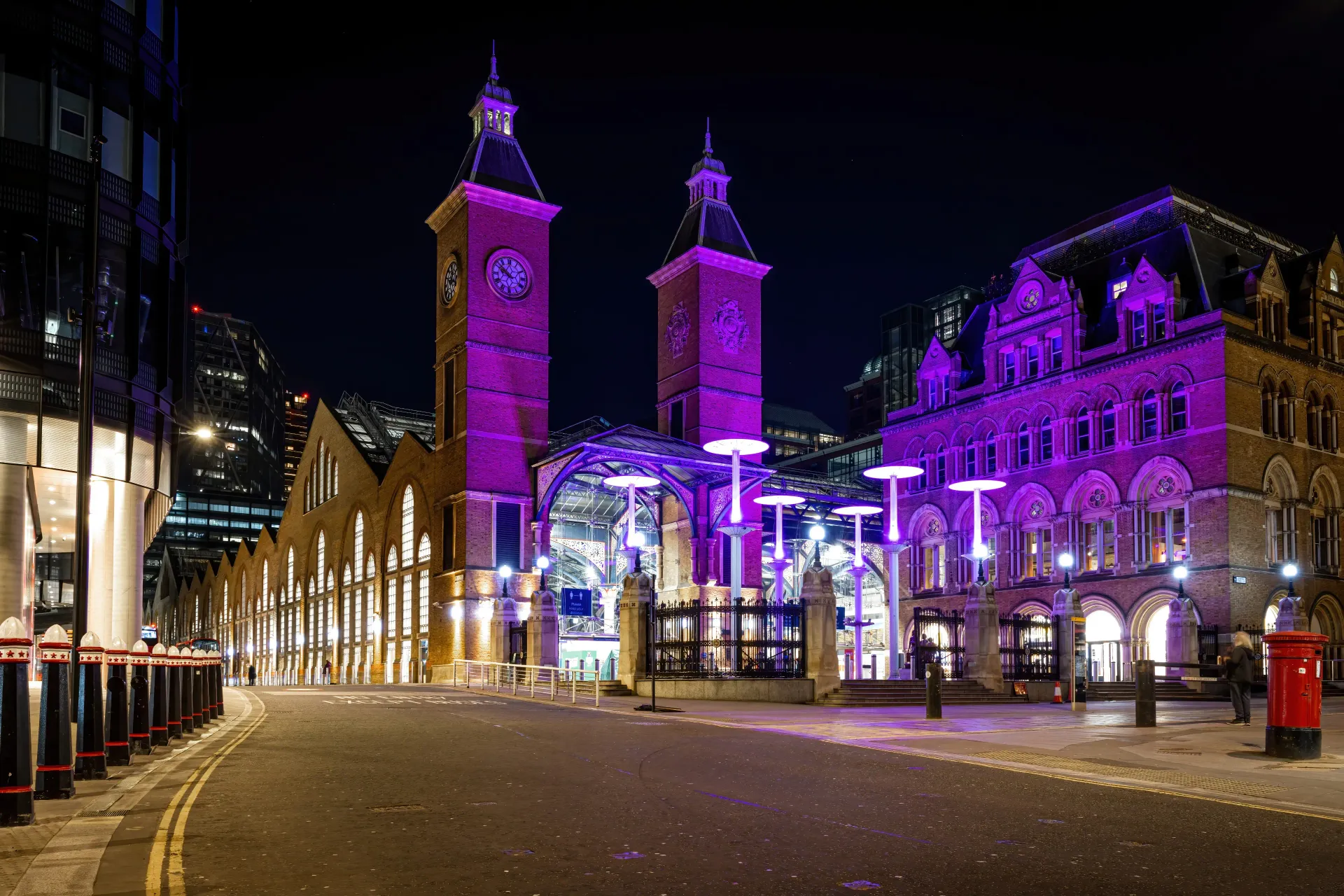 A clock tower is lit up with purple lights at night