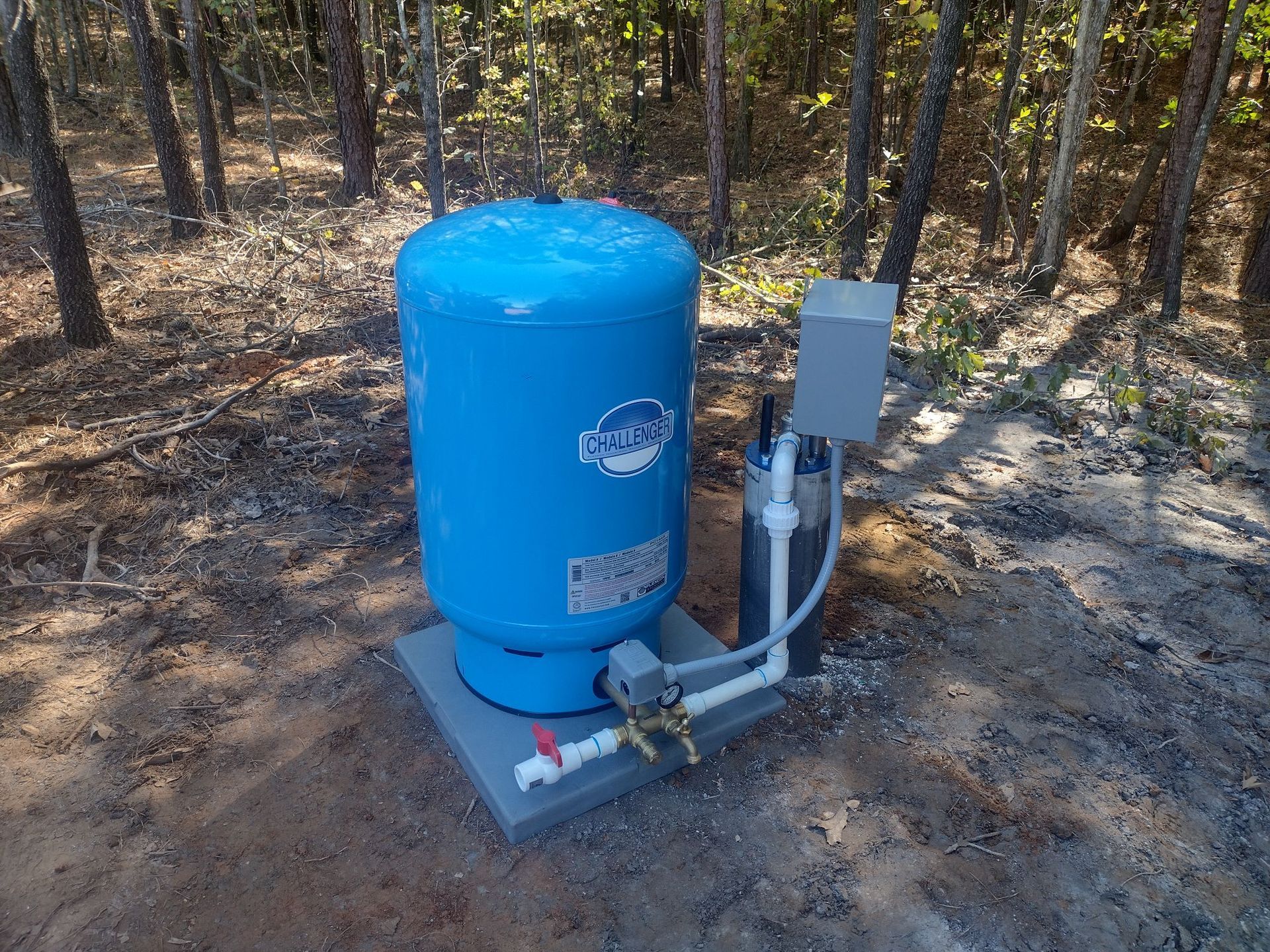 A stainless steel water pump is sitting on top of a well.