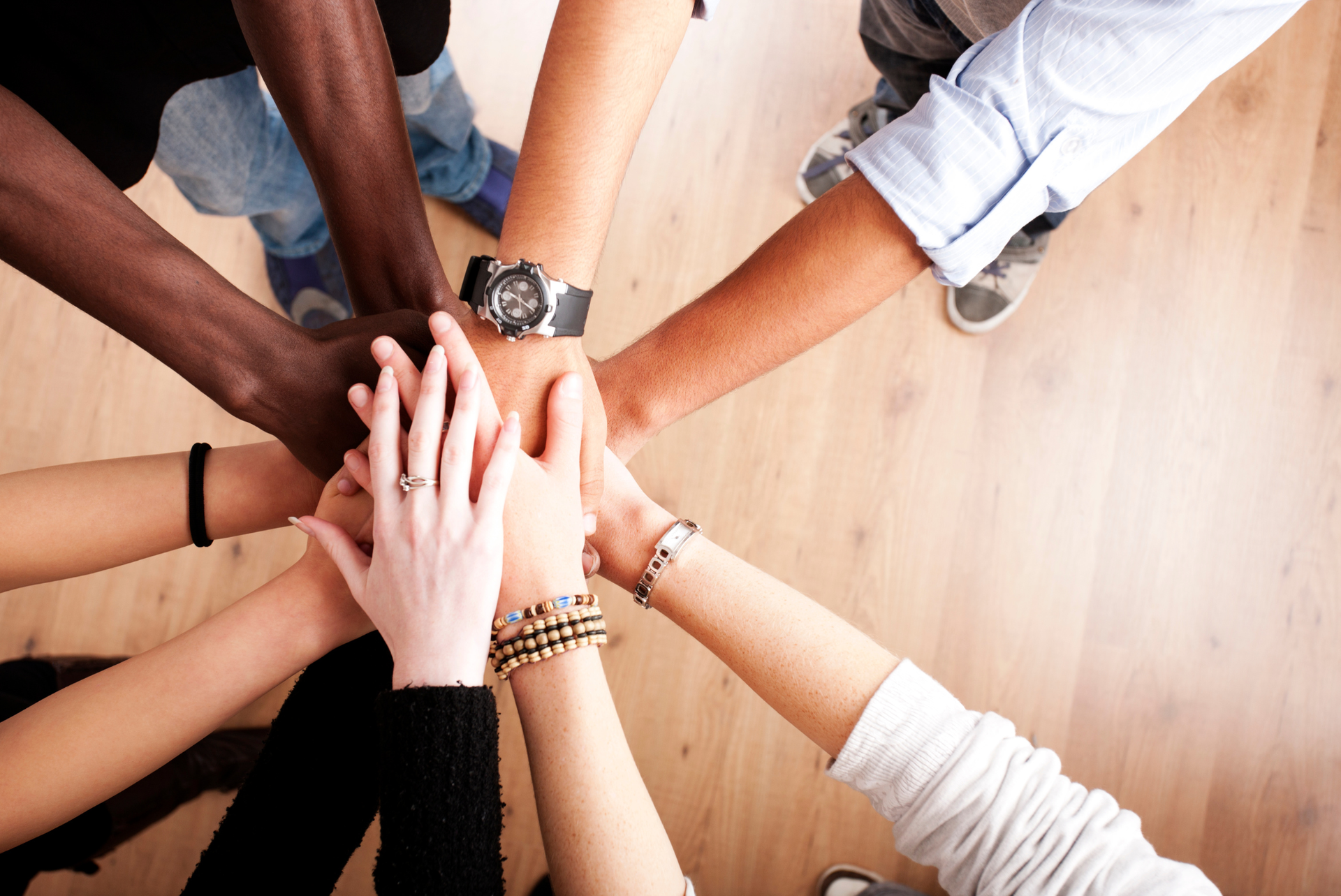 A group of people putting their hands together in a circle