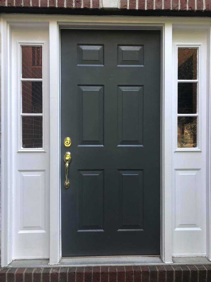 Gray six-panel front door with sidelights, white trim, and brass hardware.
