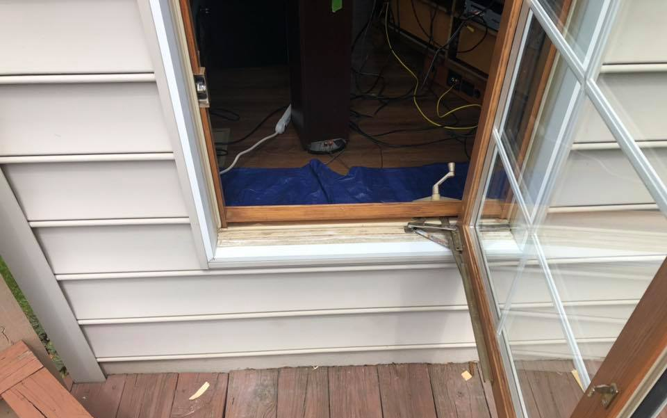 A wooden door open to an interior with wires and equipment; a blue cloth is on the floor.
