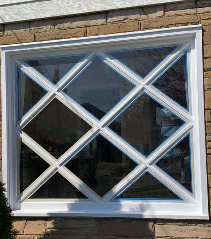 White framed window with diamond-shaped mullions, set in a stone wall.