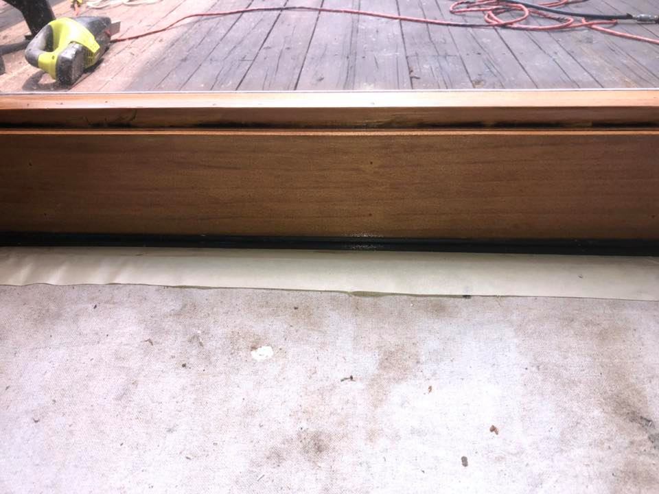 Wooden door frame with a dark line at the bottom, sitting on a light concrete floor.