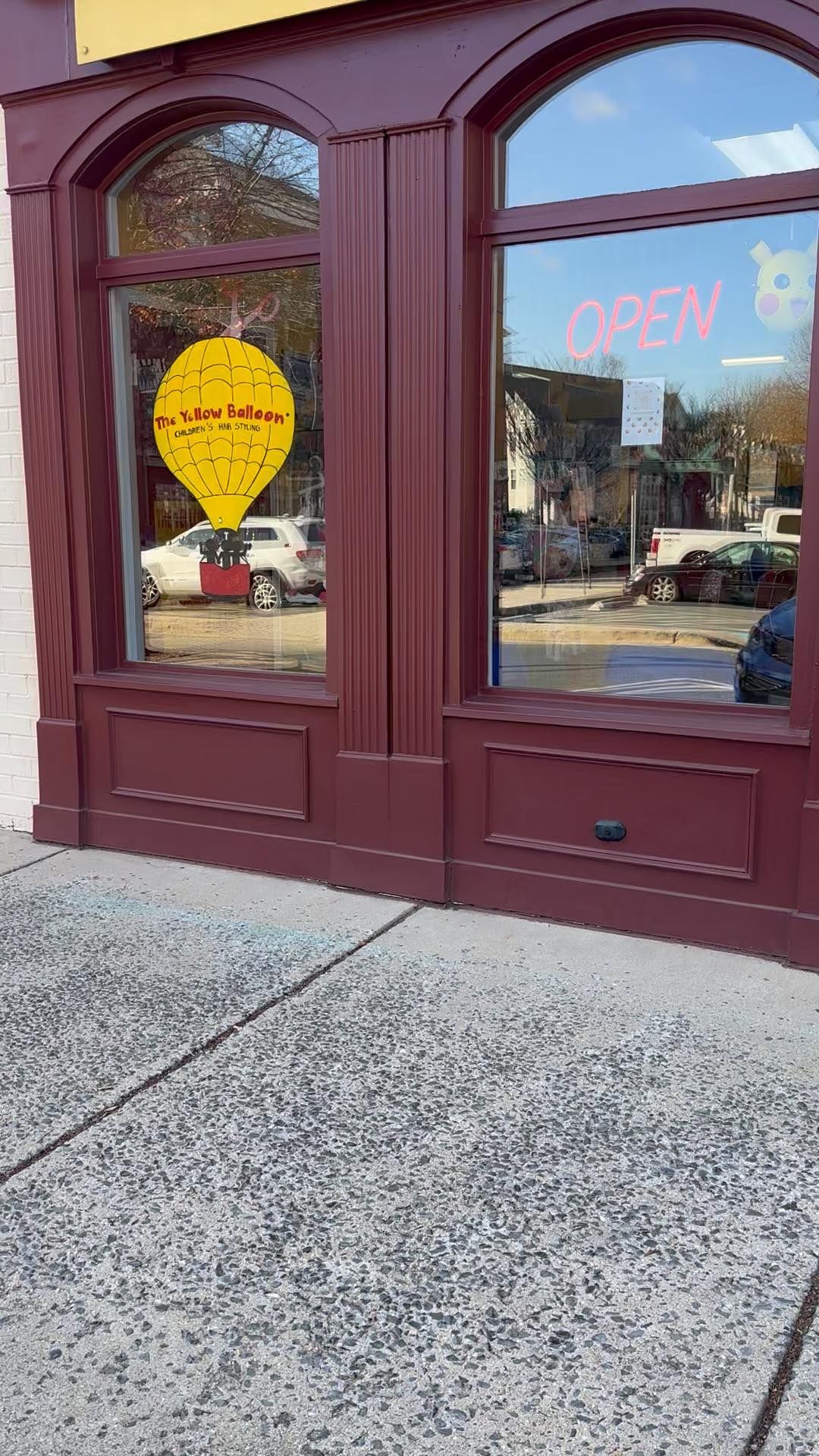 Storefront with maroon arched doors, glass windows, and an open sign on the right.