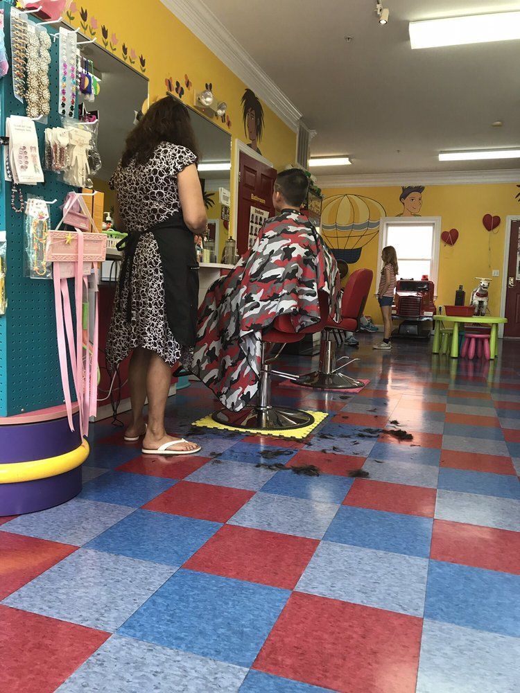 Three staff members stand in a brightly colored children’s playroom with toys and wall art.