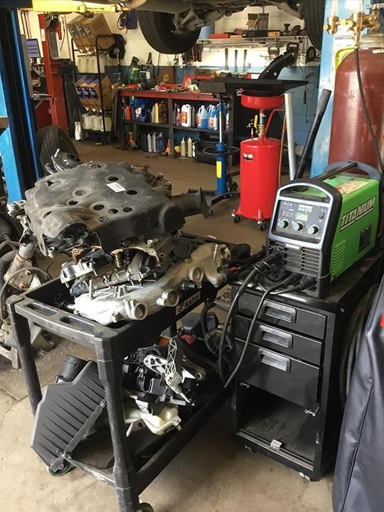 Auto repair shop with engine parts on a workbench and diagnostic equipment on a cart