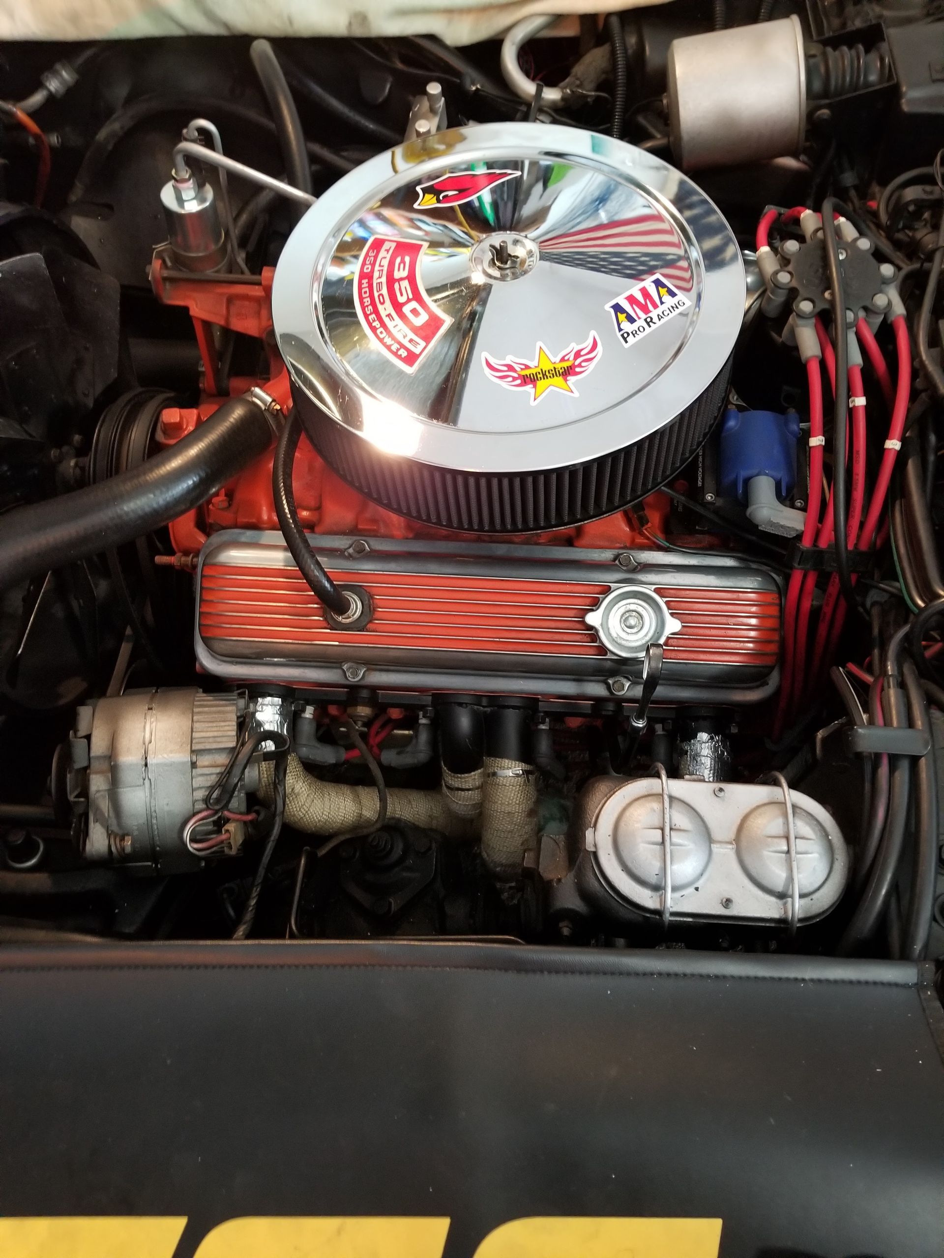 Classic car engine bay with polished chrome air cleaner and red valve covers