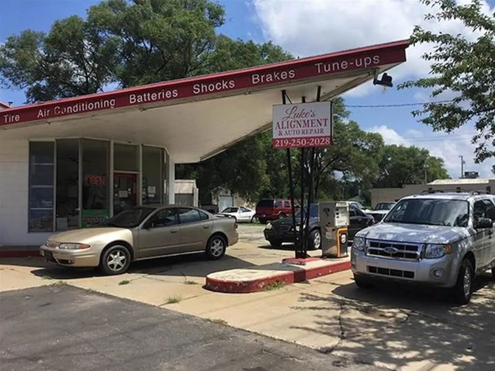 Auto repair shop with cars parked outside under a maroon awning on a sunny day