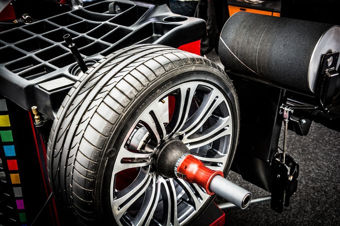 Close-up of a racing car wheel mounted on a chassis with a red axle and black tire