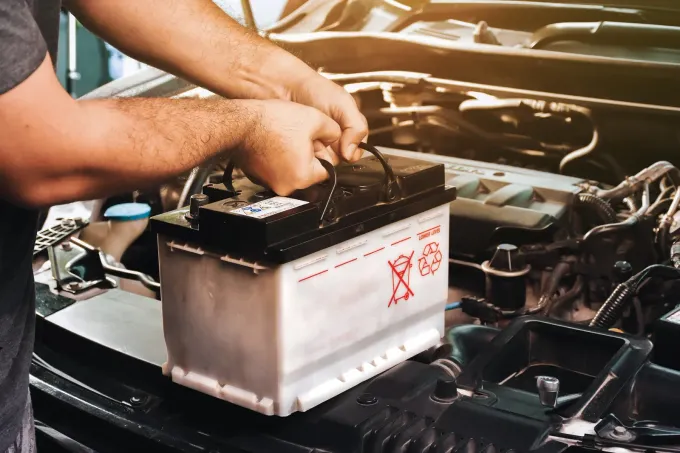 Mechanic installing a car battery in an open engine bay