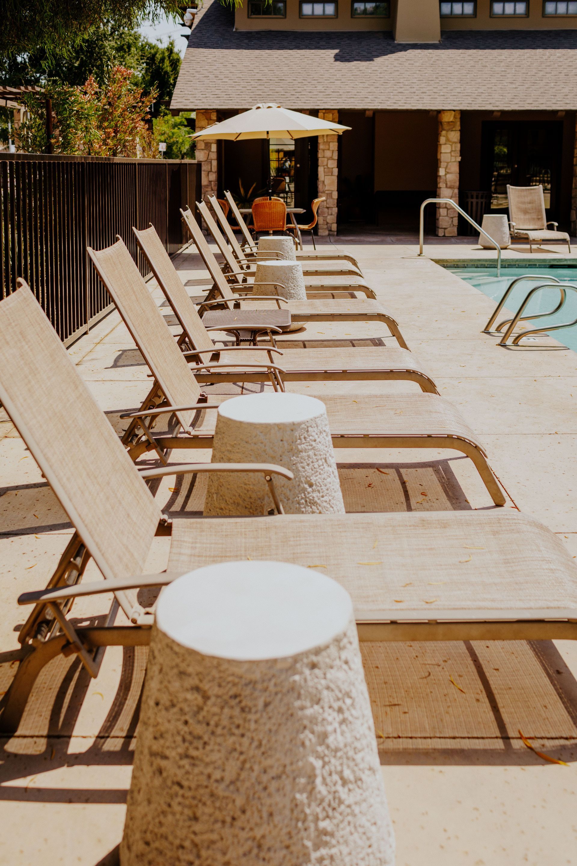 A row of lounge chairs are lined up next to a swimming pool.