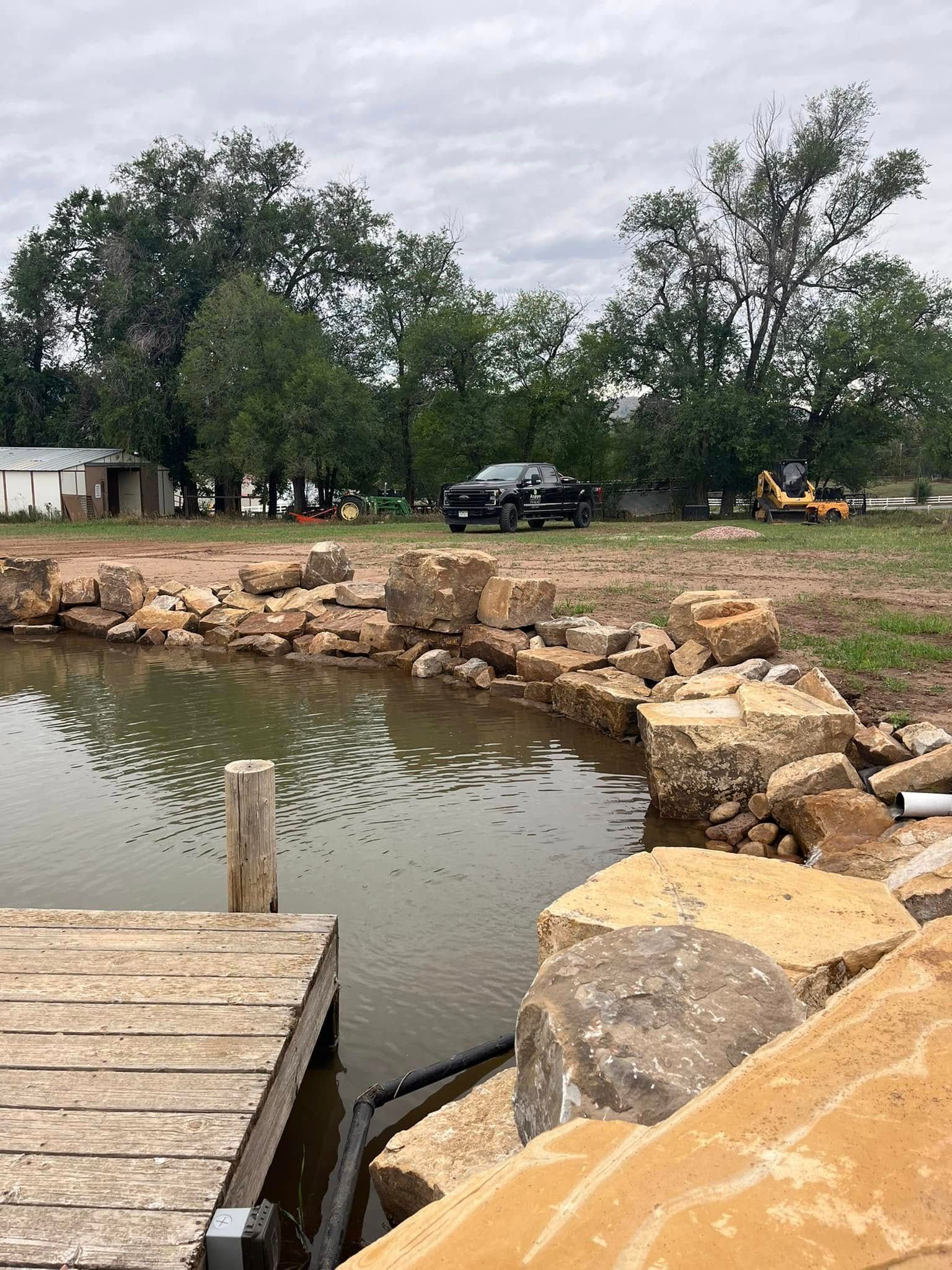 A truck is parked on the side of the road next to a pond.