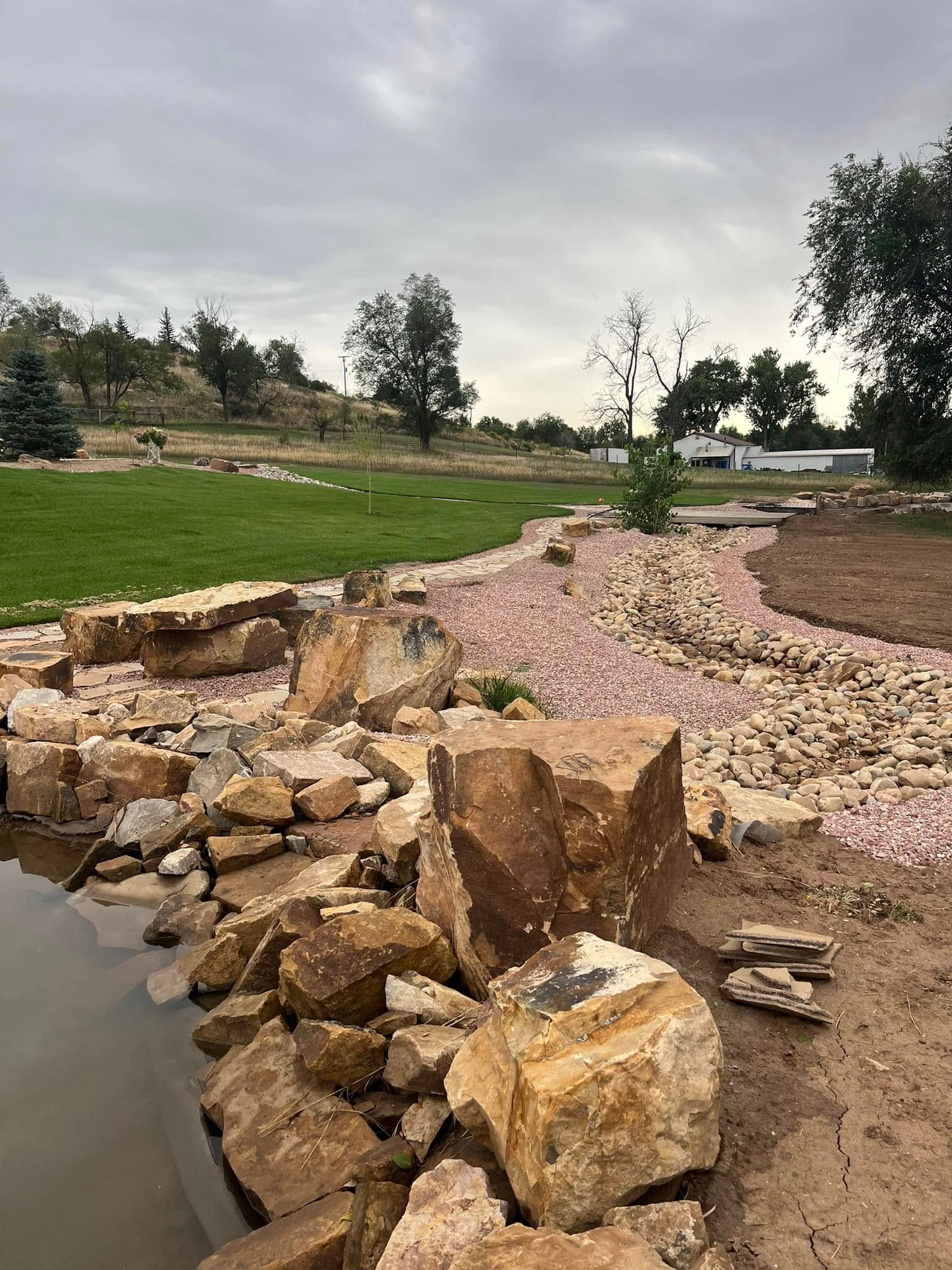 A pile of rocks sitting next to a body of water in a park.