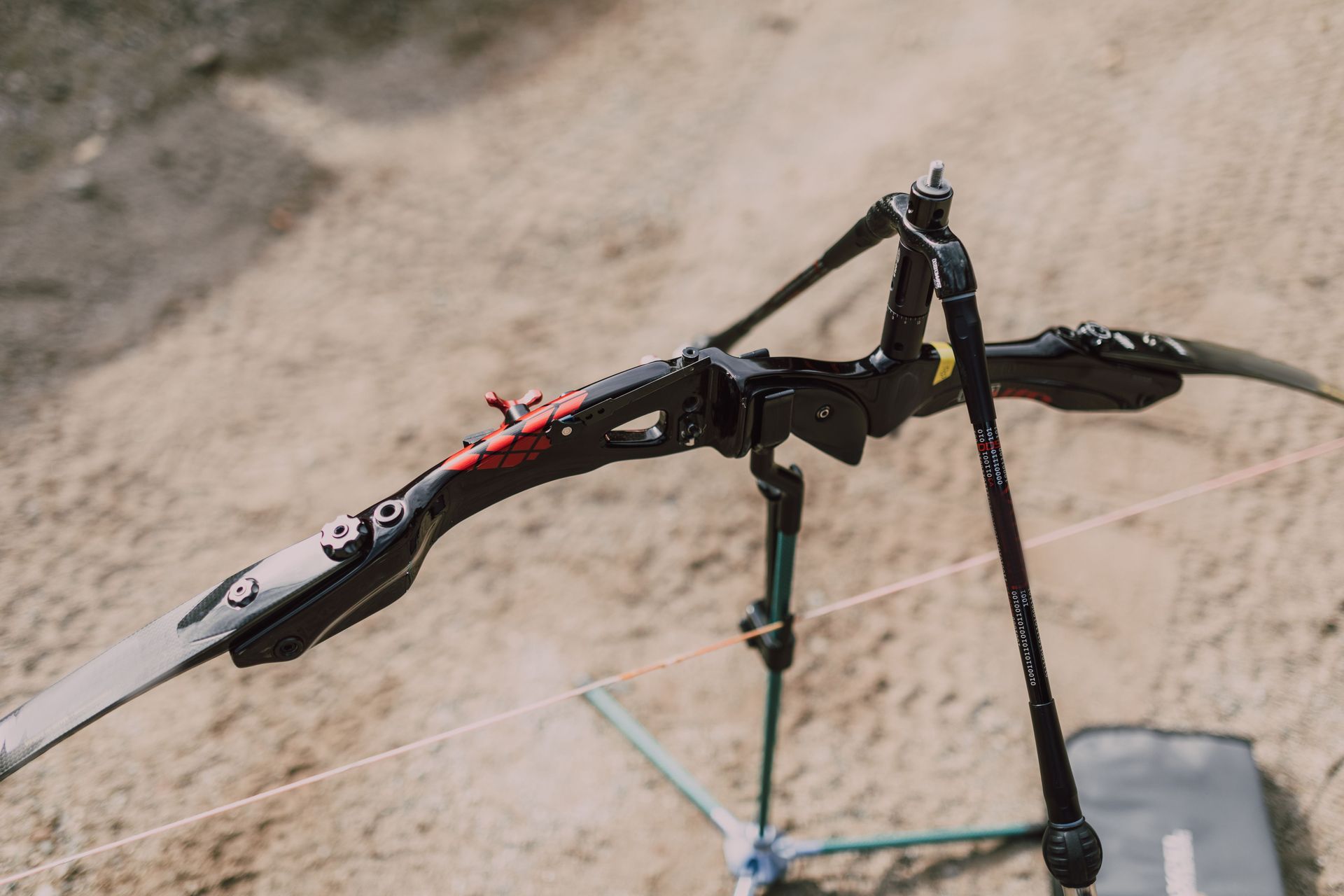 Black drone with outstretched wings hovering above a dirt trail, viewed from above