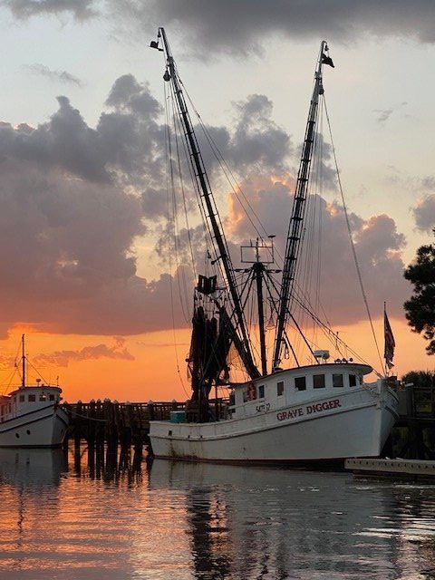 Fishing boats docked at sunset, with orange sky and reflections on calm water