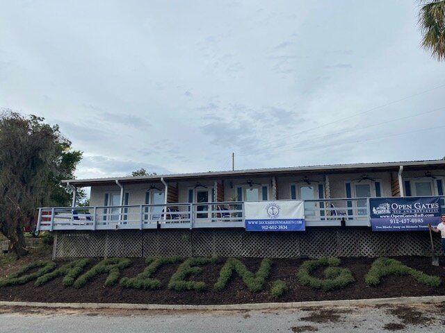 Low-rise building with banners and a grassy hillside sign under a cloudy sky