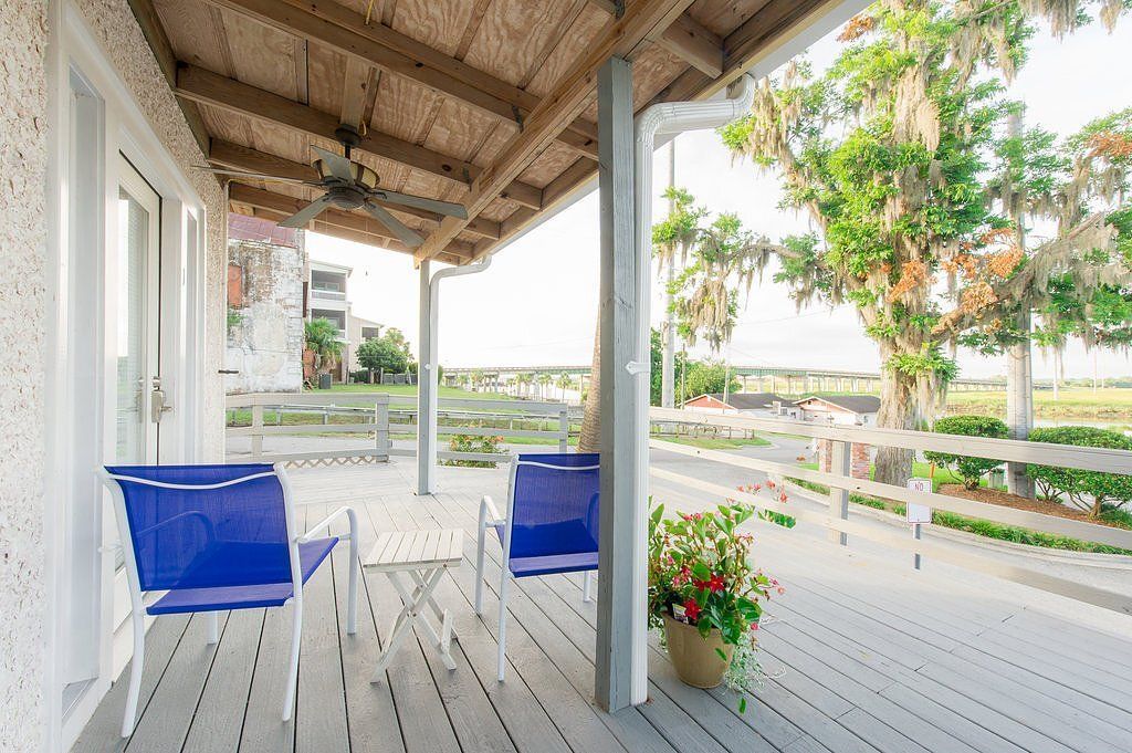 Covered porch with blue chairs, white railing, and bright countryside view