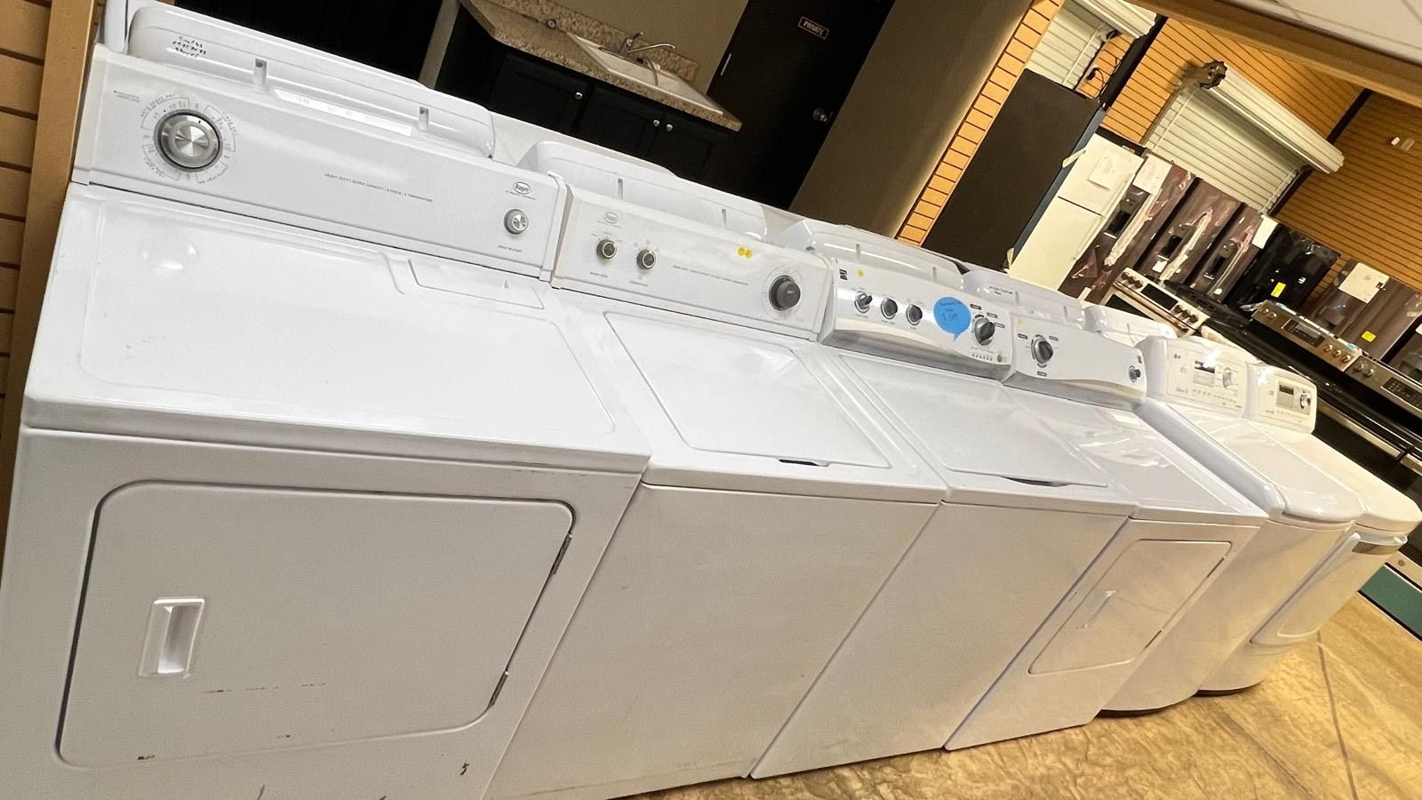 A row of white washers and dryers in a store.