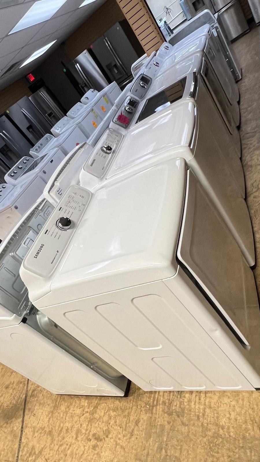 A row of white washers and dryers in a store.