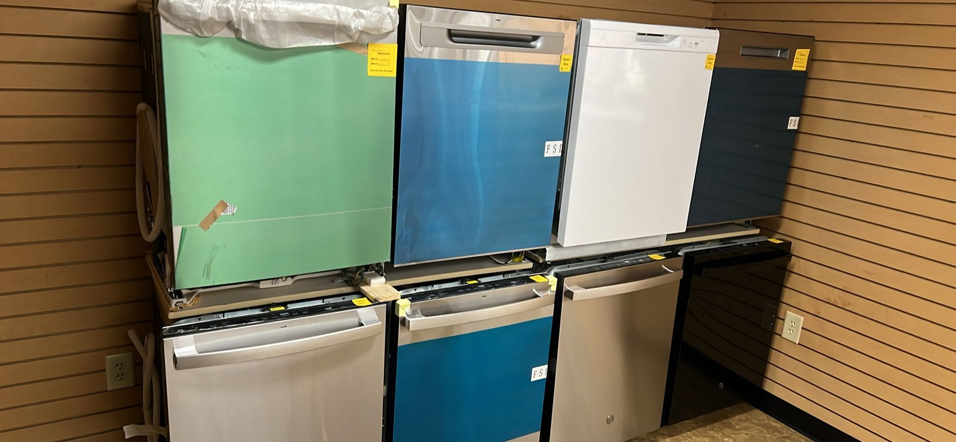 A bunch of dishwashers are sitting on top of each other in a room.