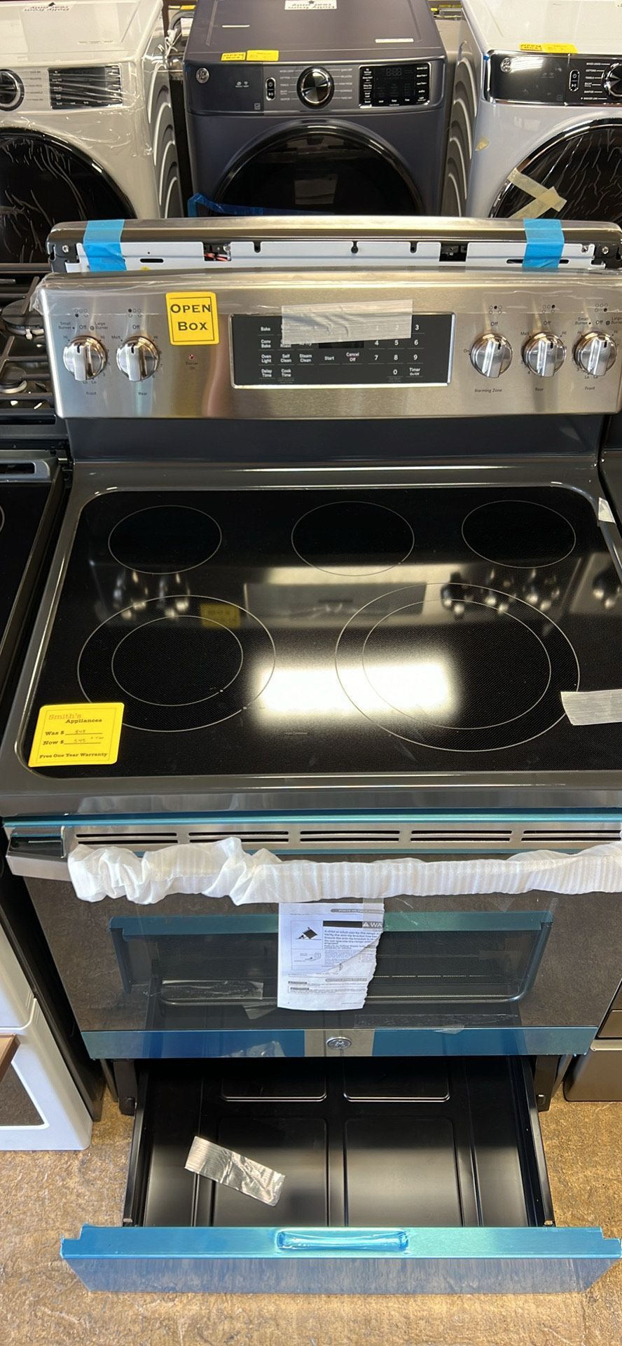A stainless steel stove with a black burner and a drawer in a store.