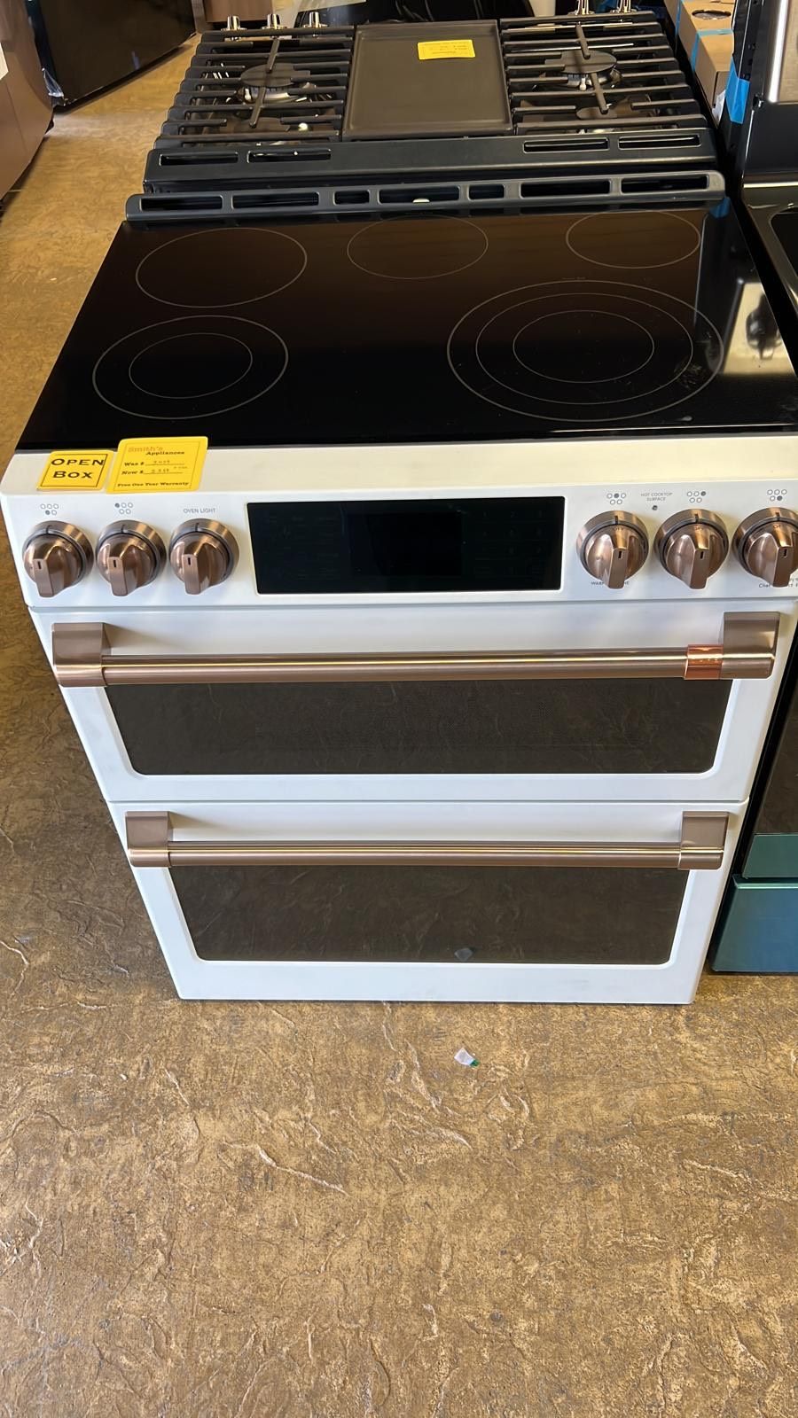 A white stove with two ovens is sitting on top of a wooden floor.
